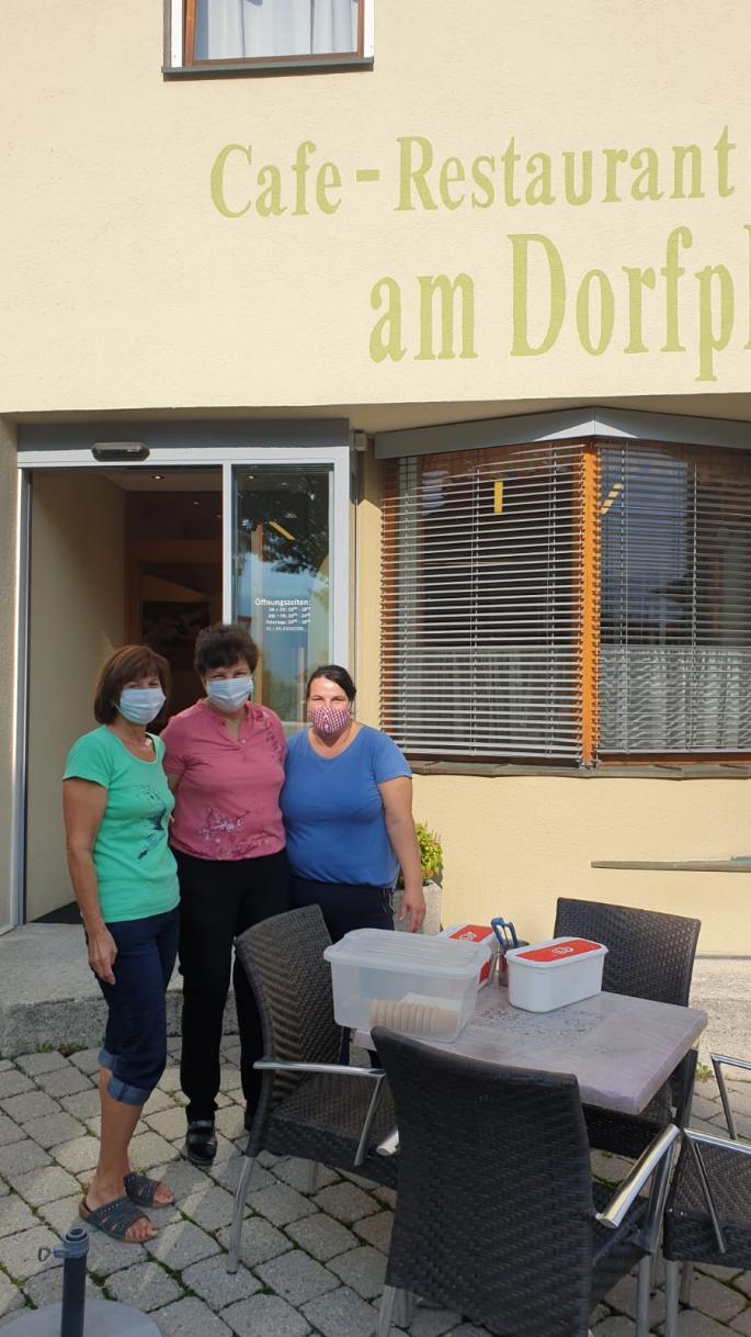 3 Personen stehen vor dem Dorfcafe