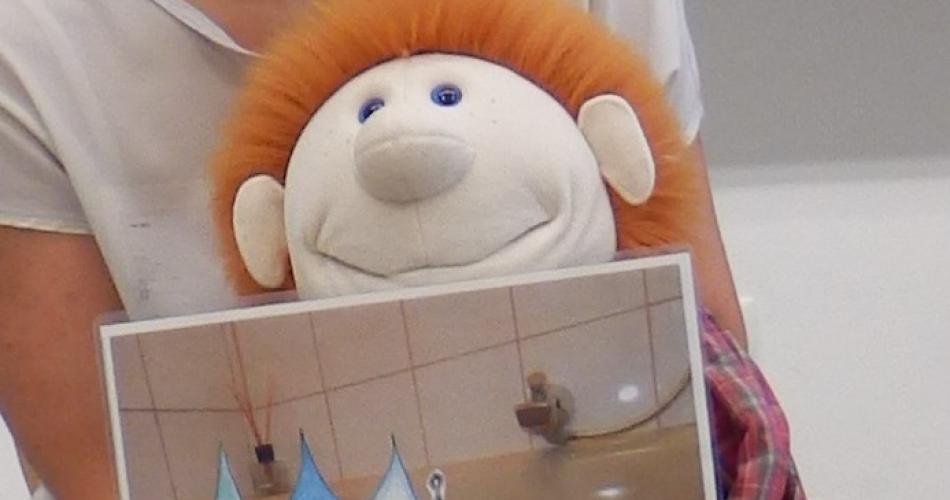 Handpuppe hält ein Bild mit Wassertropfen in der Hand